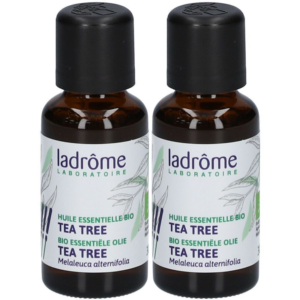 Deux flacons en verre brun avec des bouchons noirs. Les étiquettes indiquent "ladrôme LABORATOIRE" et "TEA TREE".