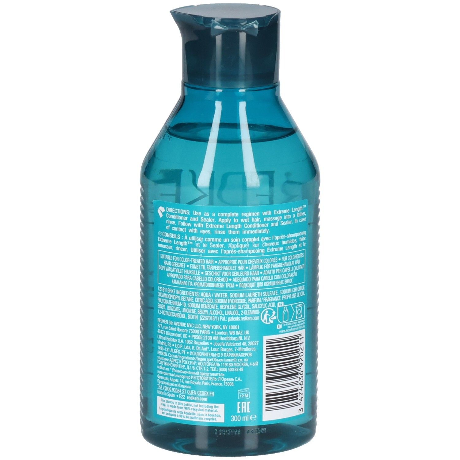 Eine durchsichtige blaue Flasche mit türkisfarbenem Verschluss, die ein Shampoo enthält. Das Etikett ist mit Produktinformationen bedruckt.
