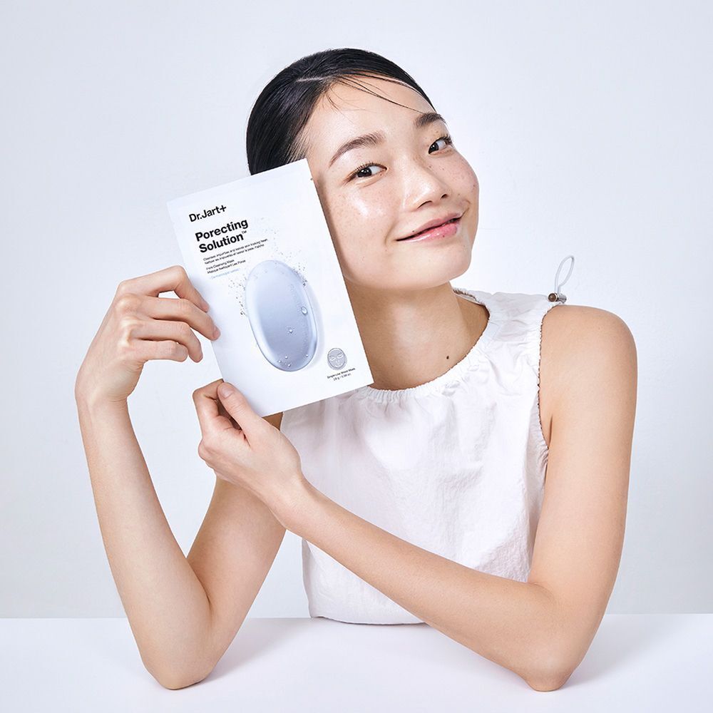 Eine Frau hält eine Dr.Jart+ Porecting Solution Maske. Die Maske ist in einer weißen Verpackung mit Produktnamen.