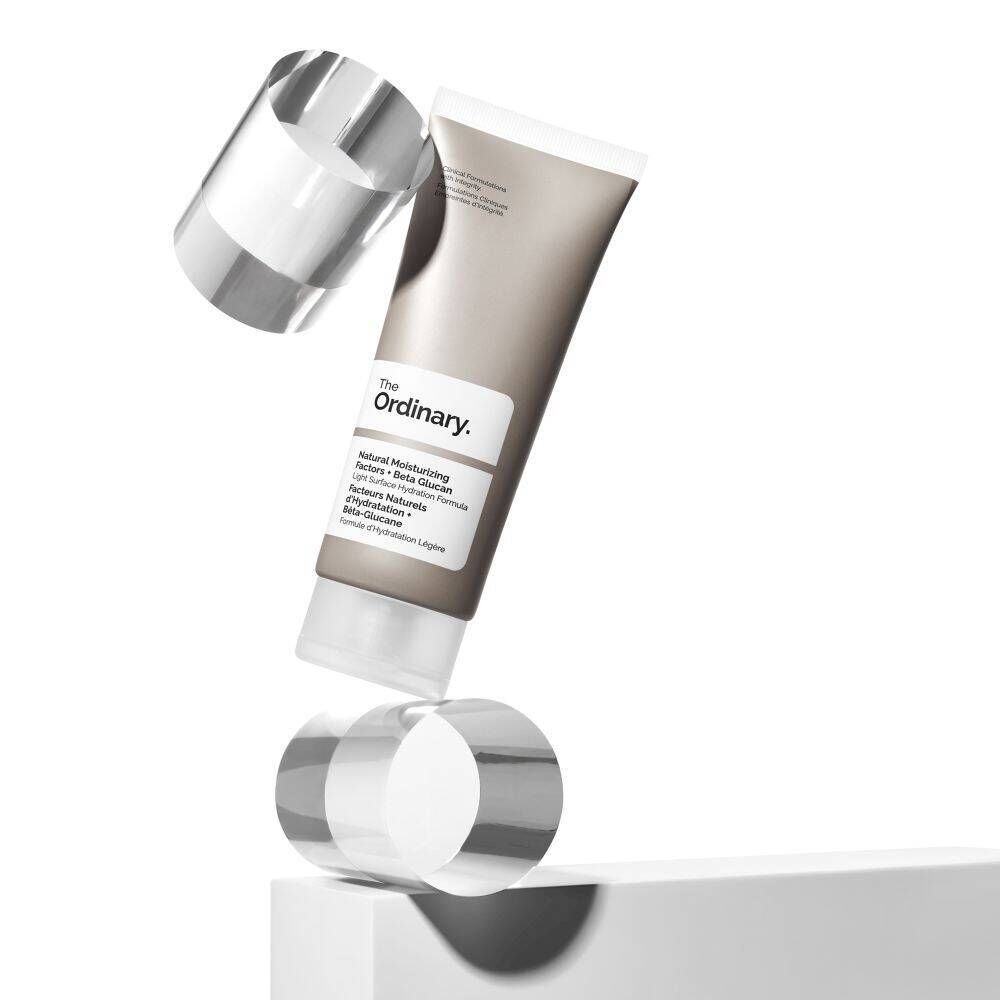 Tube in Balance mit zwei transparenten Zylindern. Aufschrift: The Ordinary, Natural Moisturizing Factors + Beta Glucan.