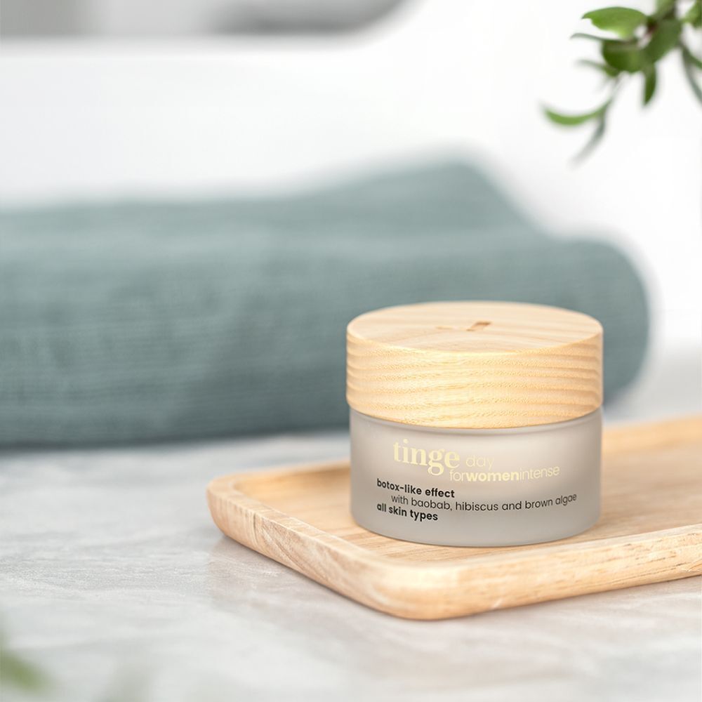 Tiegel Crème de Jour Intense auf Holztablett. Weißes Glas, Holzdeckel. Aufschrift: Tinge, botox-like effect, für alle Hauttypen.