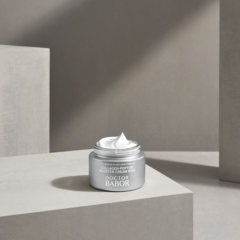 Offener silberfarbener Tiegel mit Creme. Aufschrift: Collagen-Peptide Booster Cream Rich, Doctor Babor. Steht auf einer Oberfläche.
