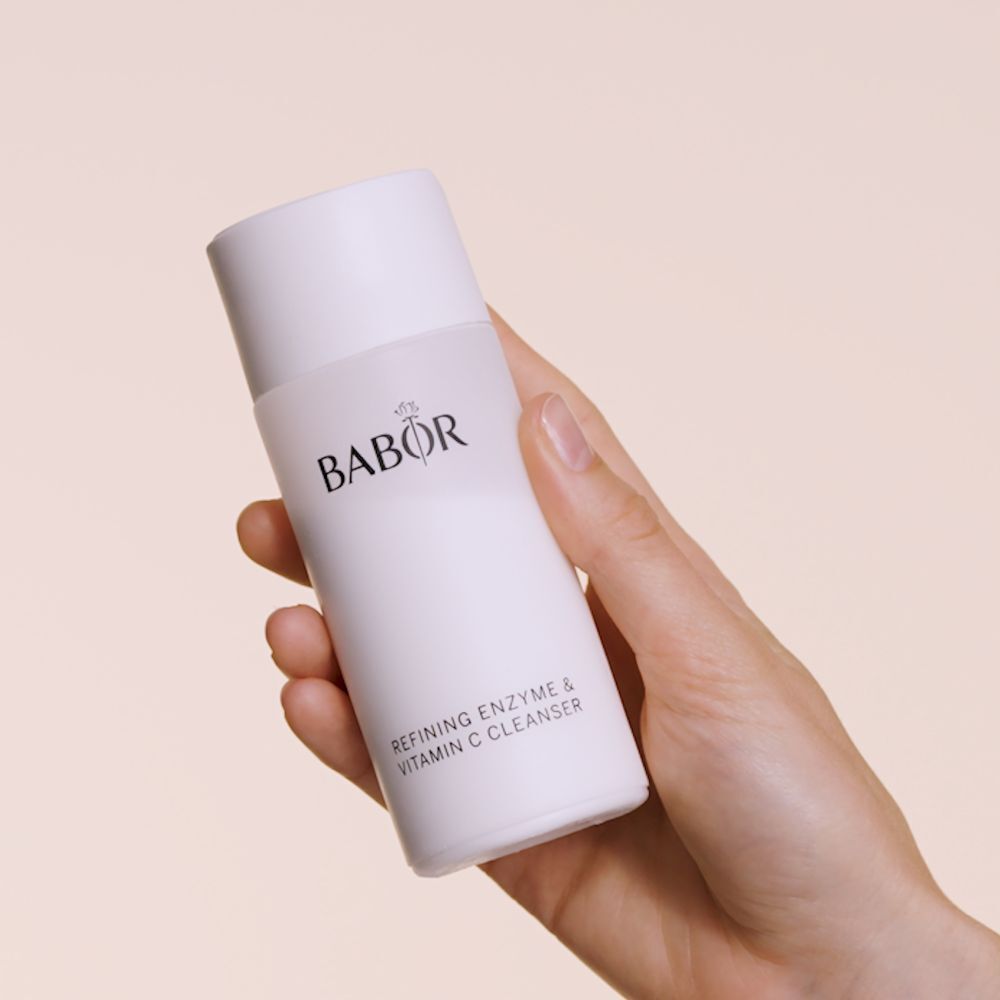 Weiße Flasche mit BABOR-Logo und Text: Refining Enzyme & Vitamin C Cleanser. In einer Hand gehalten.