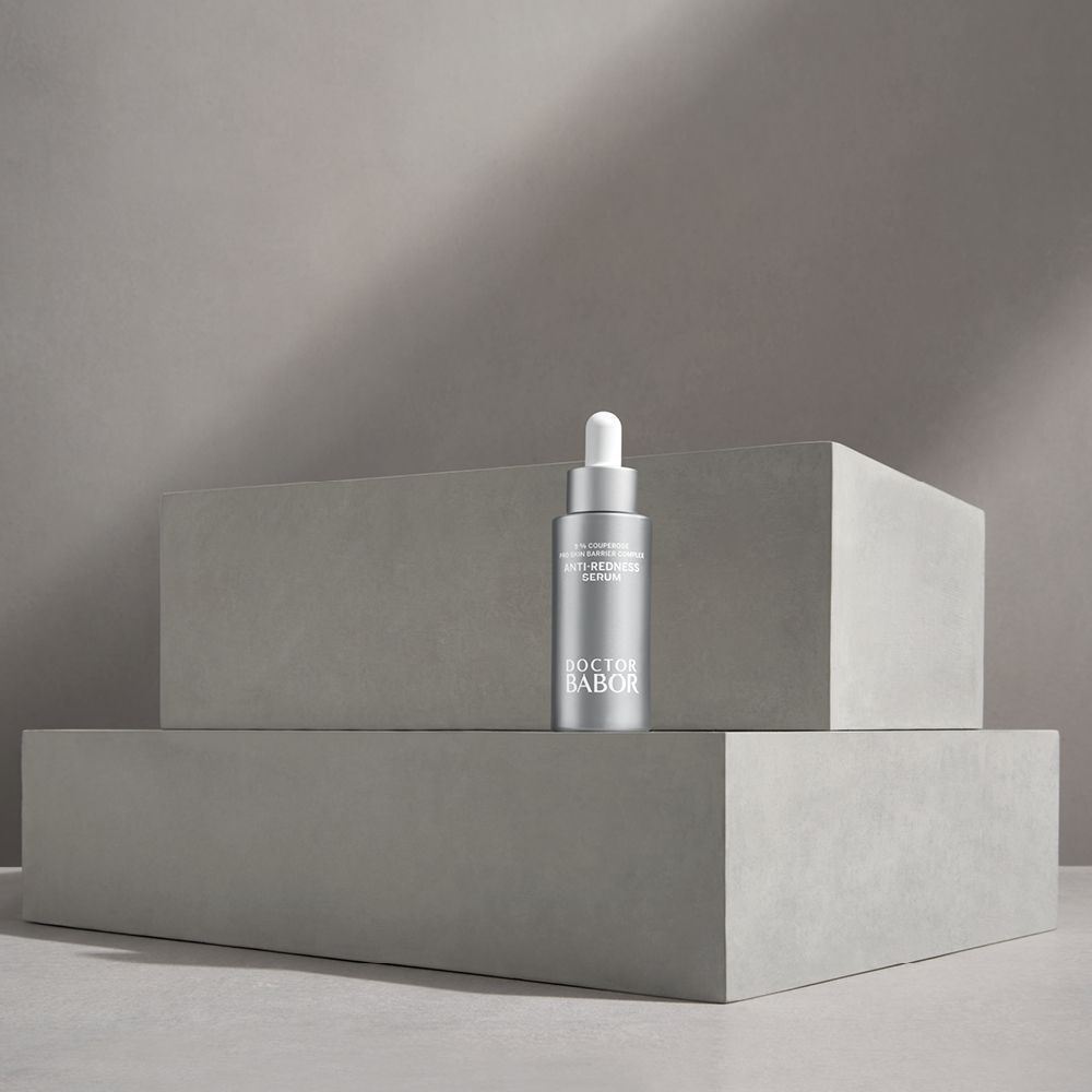 Eine silberne Flasche auf grauen Blöcken. Aufschrift: Anti-Redness Serum, Doctor BABOR.