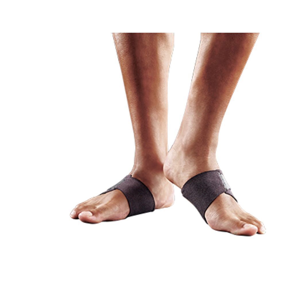 Persoon toont FUTURO™ Therapeutische ondersteuning van de voetboog op de voet. Zwarte bandage. Voeten op lichte achtergrond.