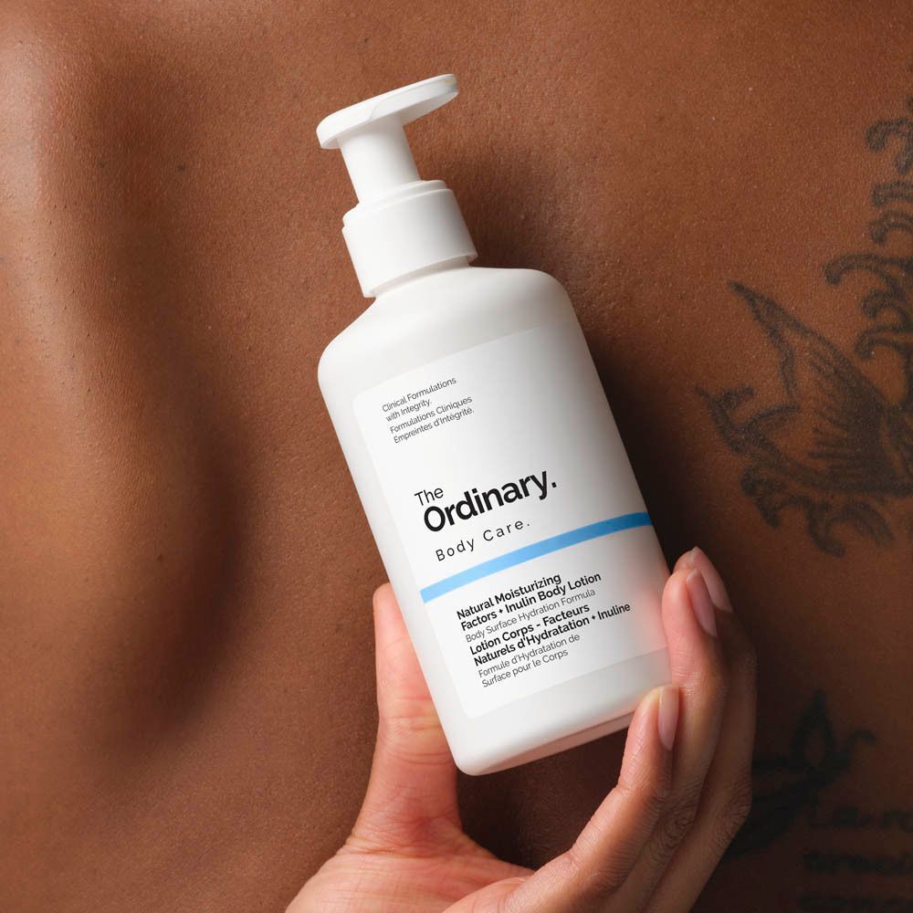 Weiße Flasche mit Pumpverschluss. Aufschrift: The Ordinary, Body Care, Natural Moisturizing Factors + Inulin Body Lotion. In Hand gehalten.