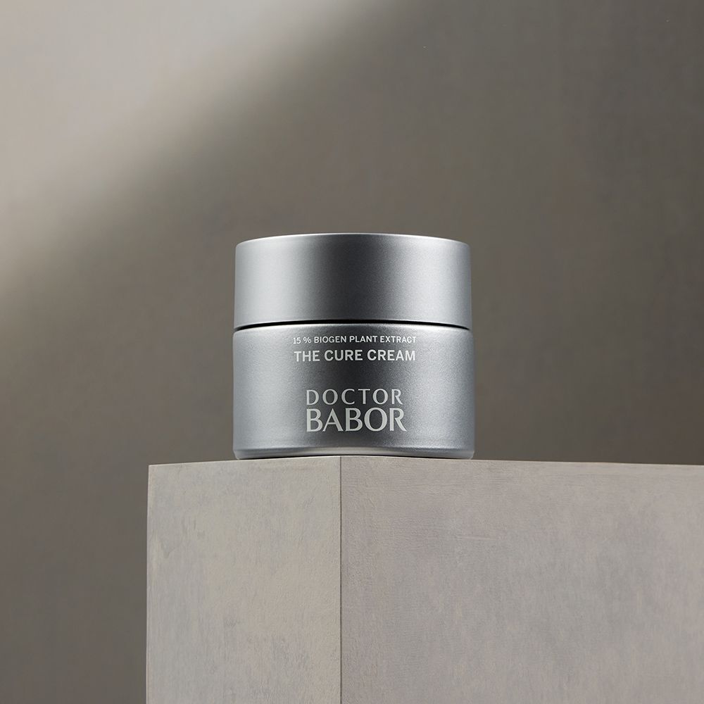 Silberfarbener Tiegel mit Aufschrift THE CURE CREAM und DOCTOR BABOR auf einer Oberfläche.