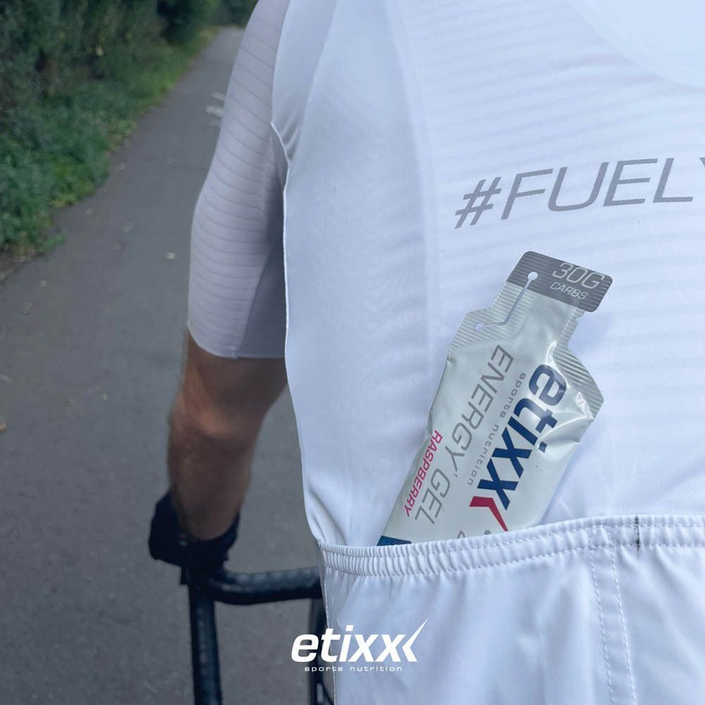 Une personne avec un Etixx Energy Gel Framboise dans la poche arrière. Inscription : Etixx, Energy Gel, Framboise.