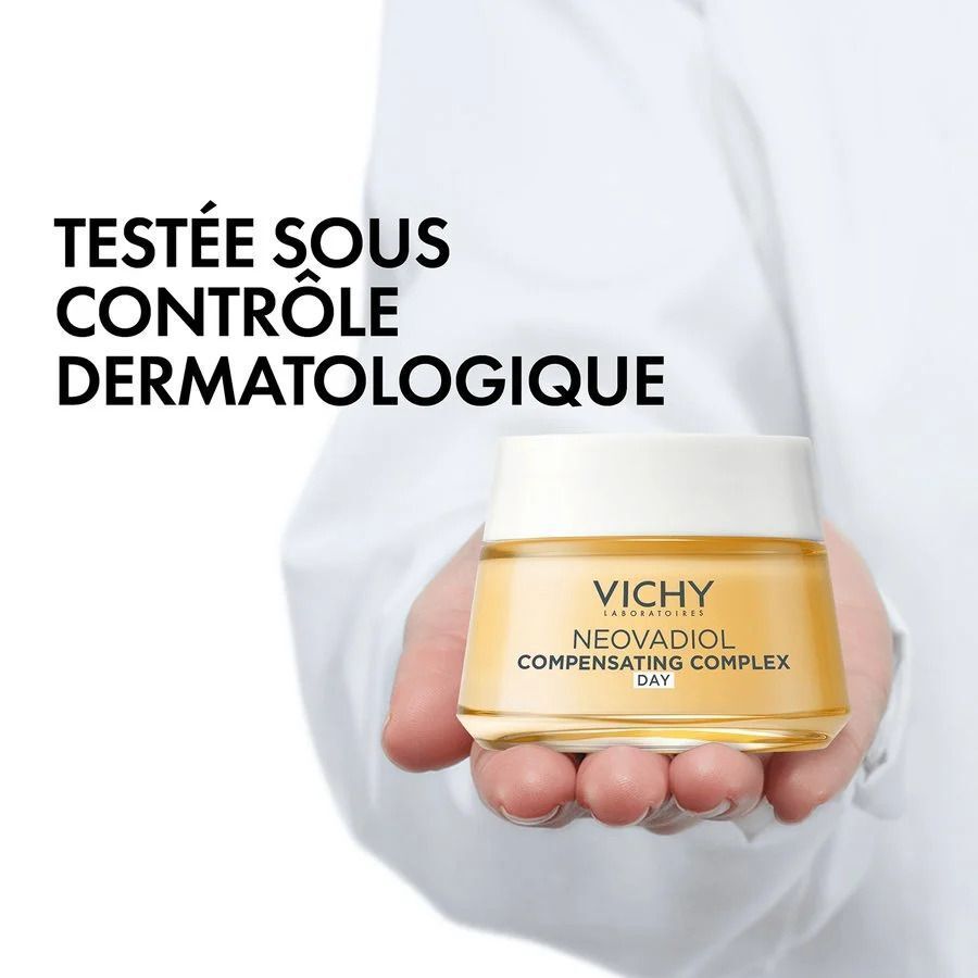 Main tenant un pot de Vichy Neovadiol Compensating Complex Day. Texte: Testé sous contrôle dermatologique.
