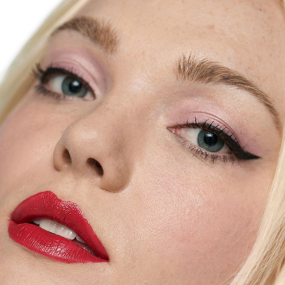 Porträt einer Frau mit geschminkten Augen und roten Lippen, die Clinique Quickliner für Augenbrauen verwendet.