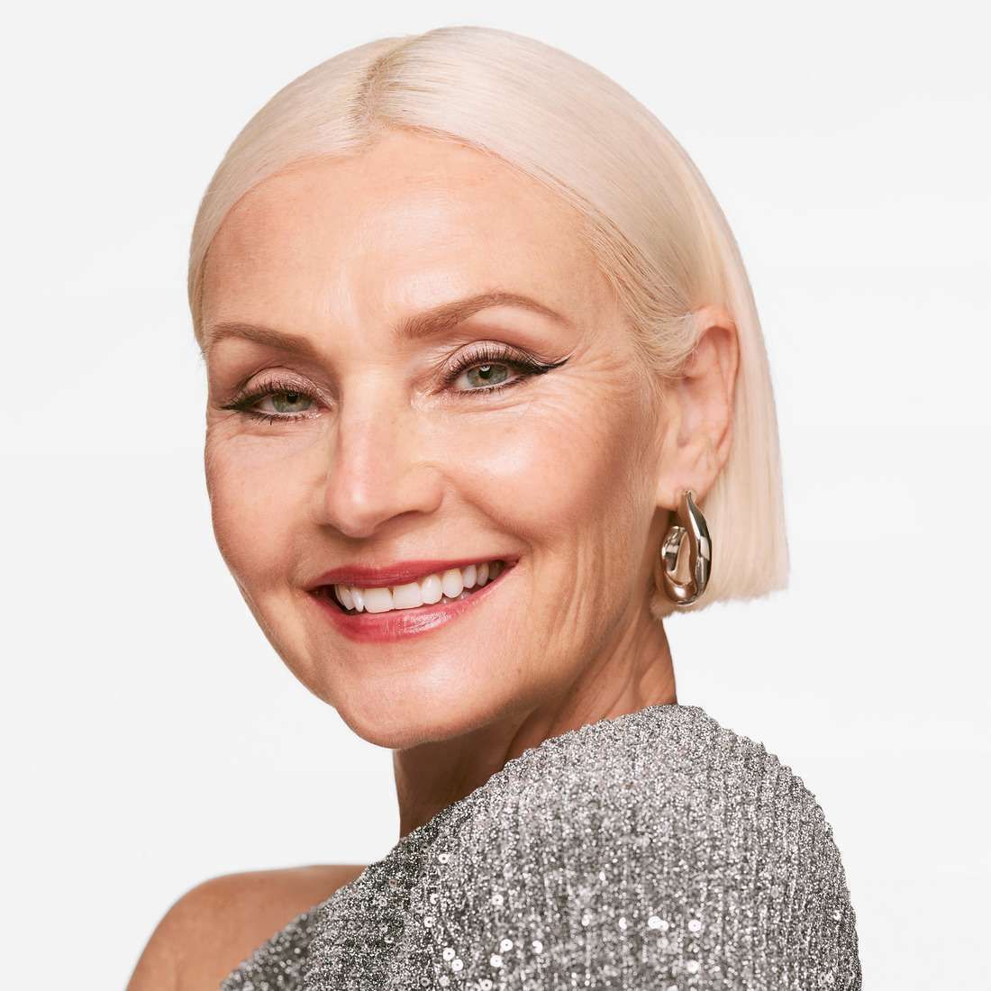 Porträt einer stilvollen älteren Frau mit Make-up und Ohrringen.