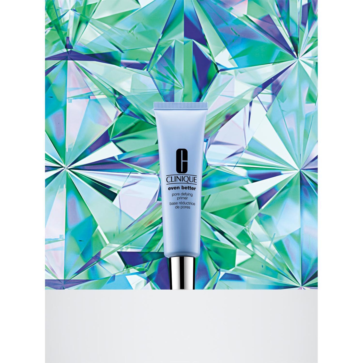 Eine Tube CLINIQUE Even Better Pore Defying Primer vor einem facettenreichen, grünen Hintergrund.