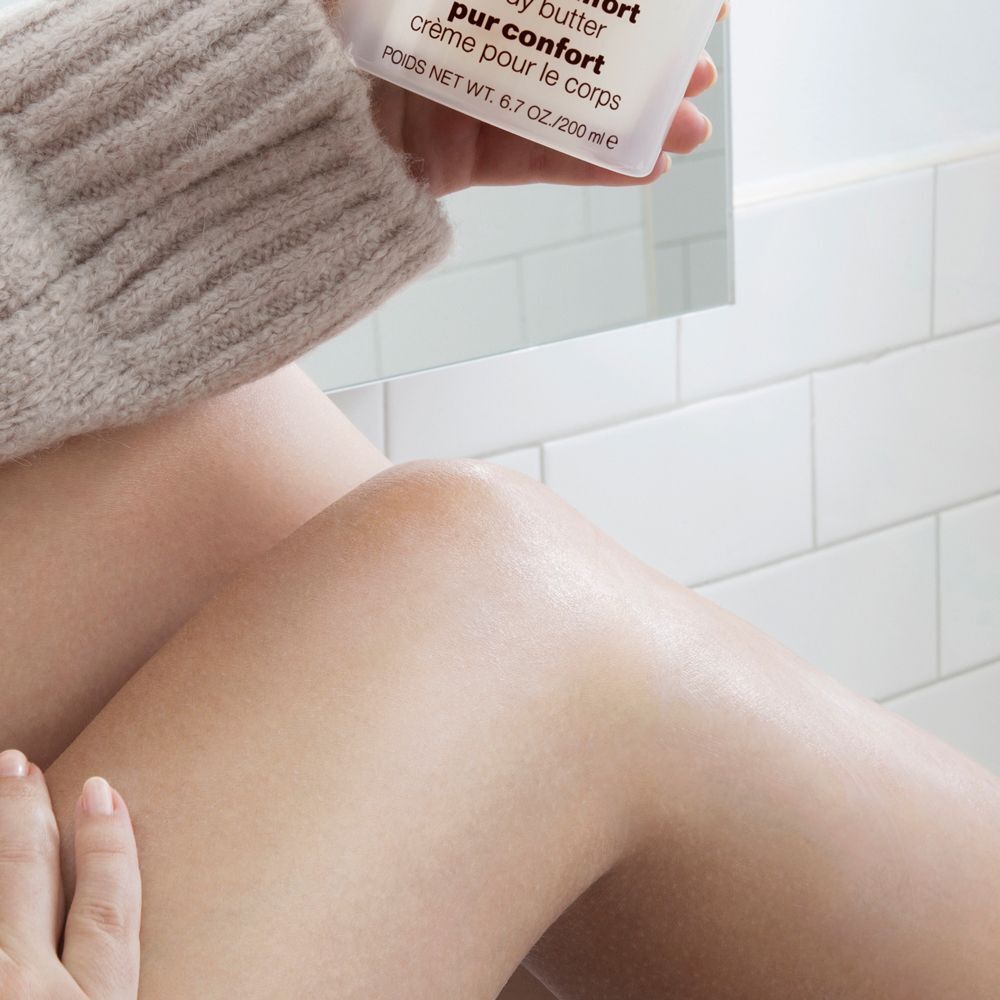 Eine Person trägt Clinique Deep Comfort Body Butter auf ihre Beine auf.