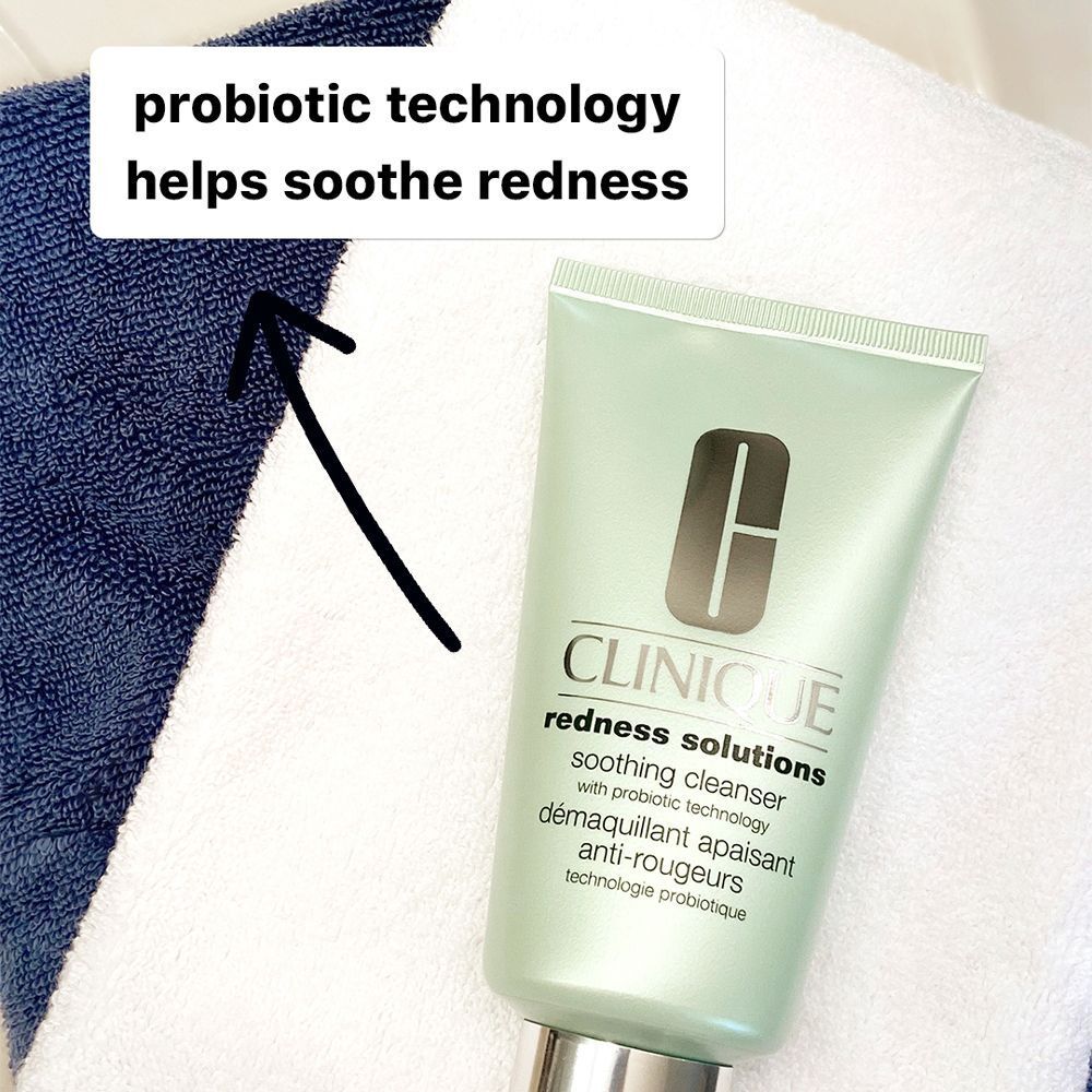 Eine CLINIQUE Redness Solutions beruhigende Reiniger-Tube neben blauen und weißen Handtüchern.