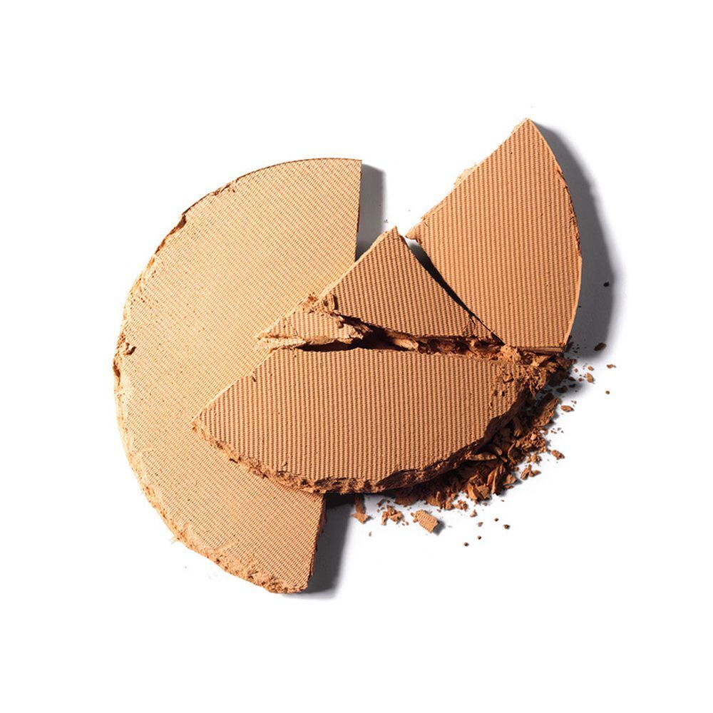 Ein zerbrochener, runder hellbrauner Puder mit Rillenstruktur.