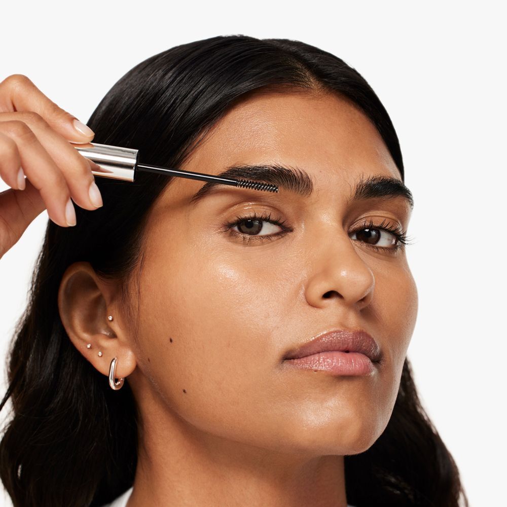 Eine Person trägt Clinique Just Browsing Clear Sculpting Gel auf die Augenbrauen auf.