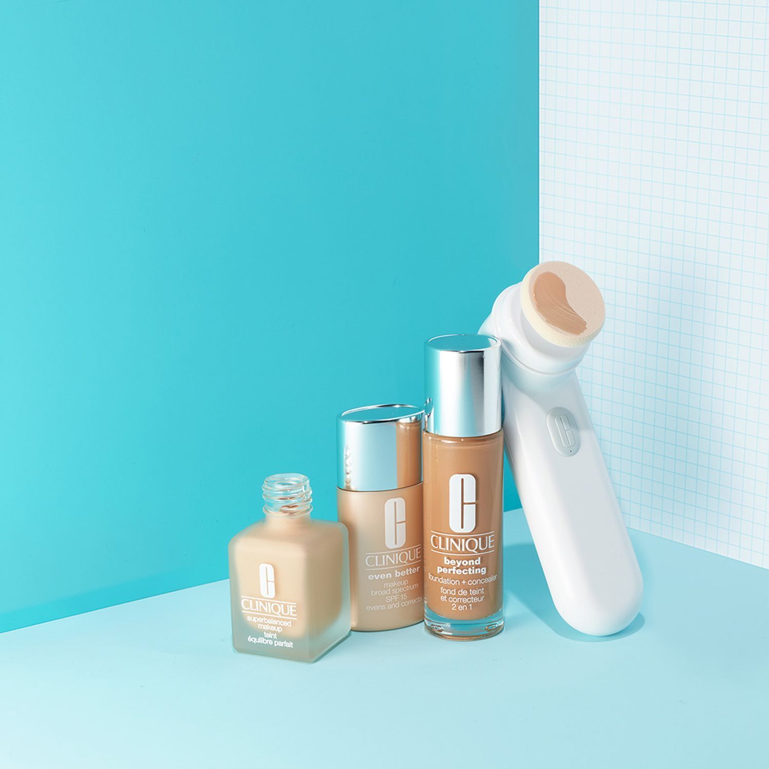 Drei Flaschen Clinique Beyond Perfection Make-Up und ein Hautpflegegerät.