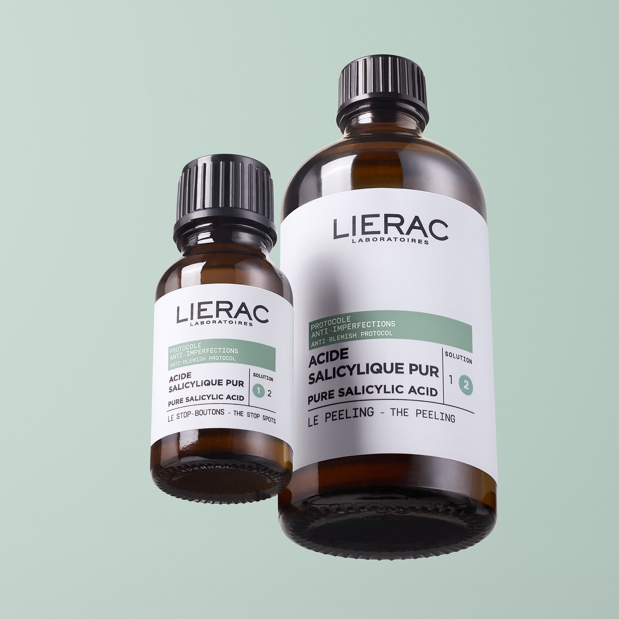 Twee bruine flessen met zwarte dop. Etiket met productnaam en tekst. Merk: Lierac.