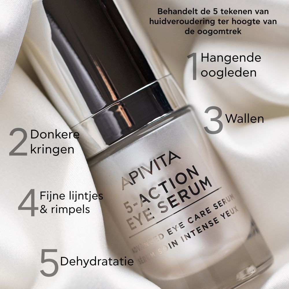Apivita 5-Action Eye Serum op witte stof. Tekst: Apivita, 5-Action Eye Serum. Labels: hangende oogleden, donkere kringen, wallen, fijne lijntjes, dehydratatie.