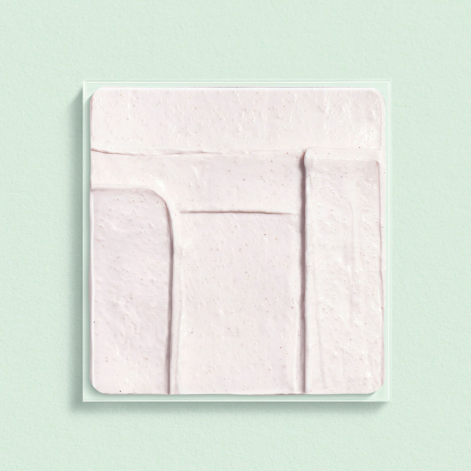 Échantillon carré de crème rose sur fond vert.