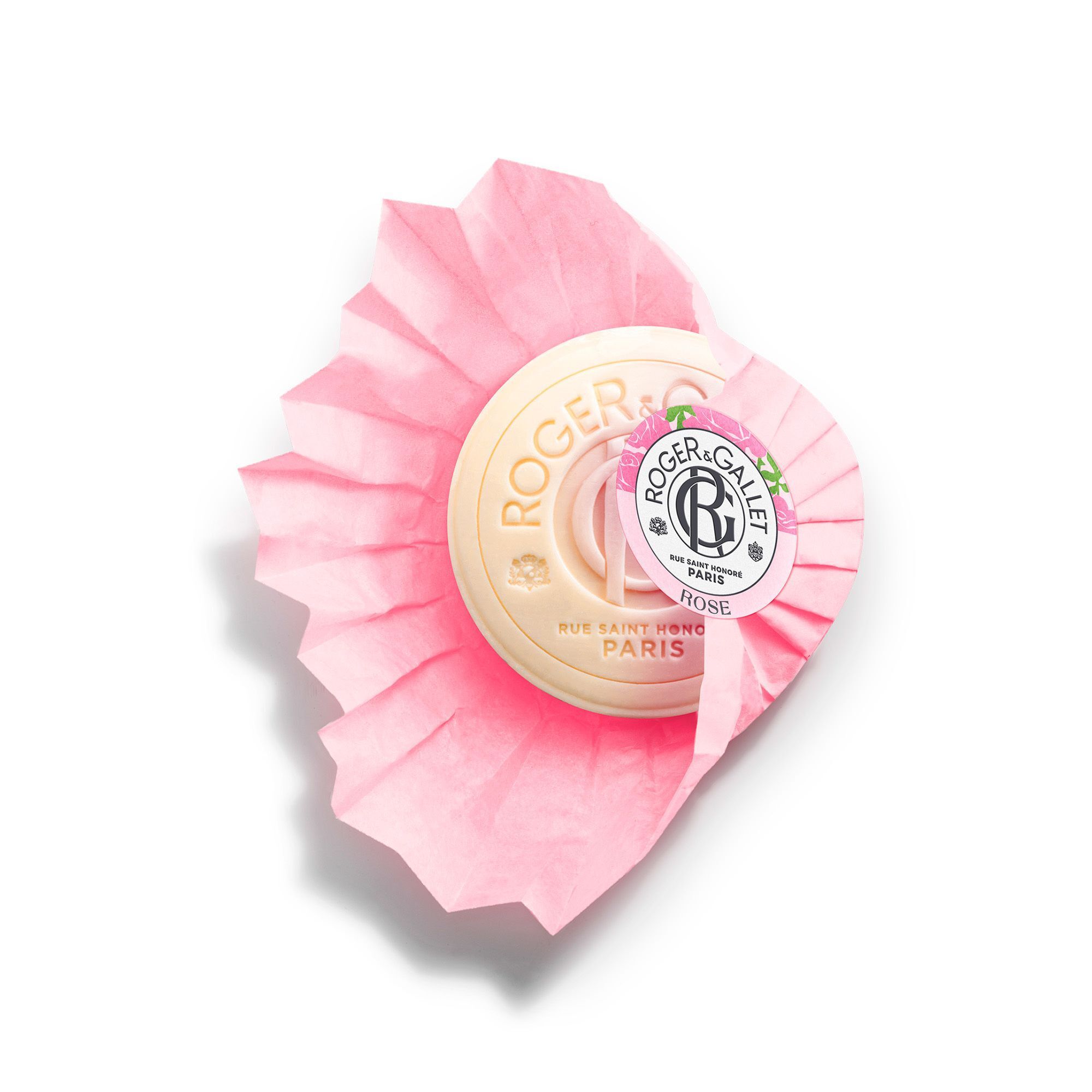 Savon rond crème sur papier plié rose. Inscription: Roger & Gallet, Rose. Logo et texte.