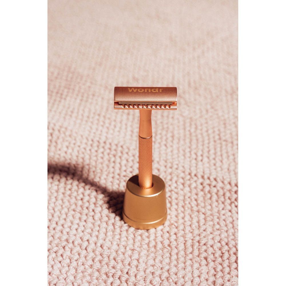 Rosegouden safety razor met handvat en standaard.