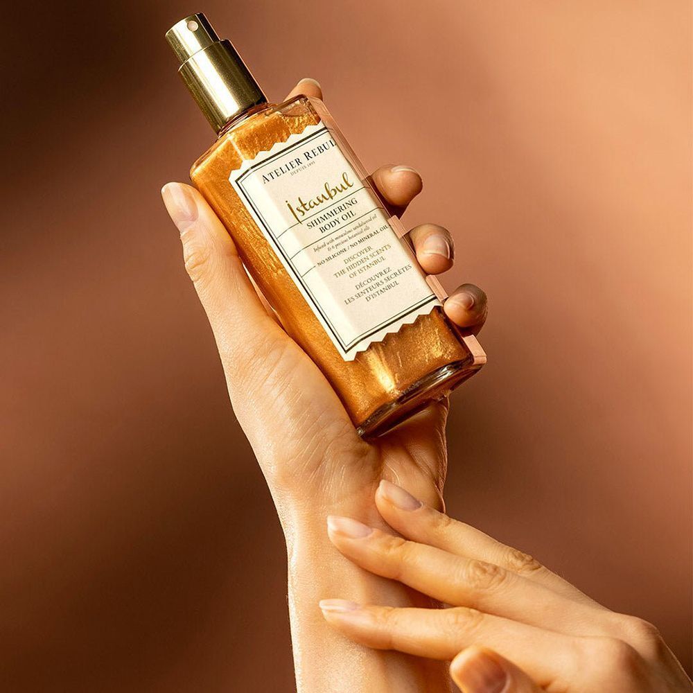 Eine Hand hält ATELIER REBUL Istanbul Shimmering Body Oil.