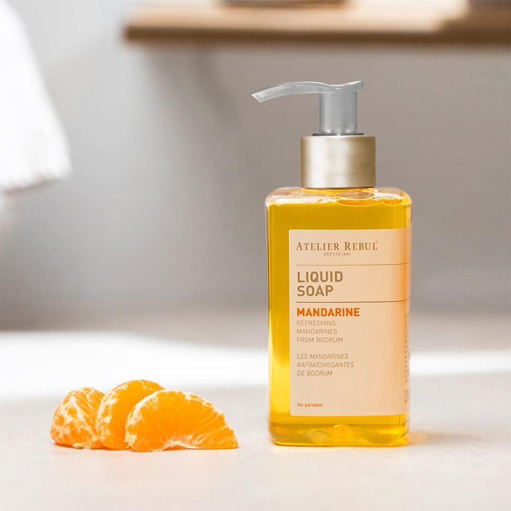 Eine Atelier Rebul Flüssigseife Mandarine mit drei Mandarinenstücken.