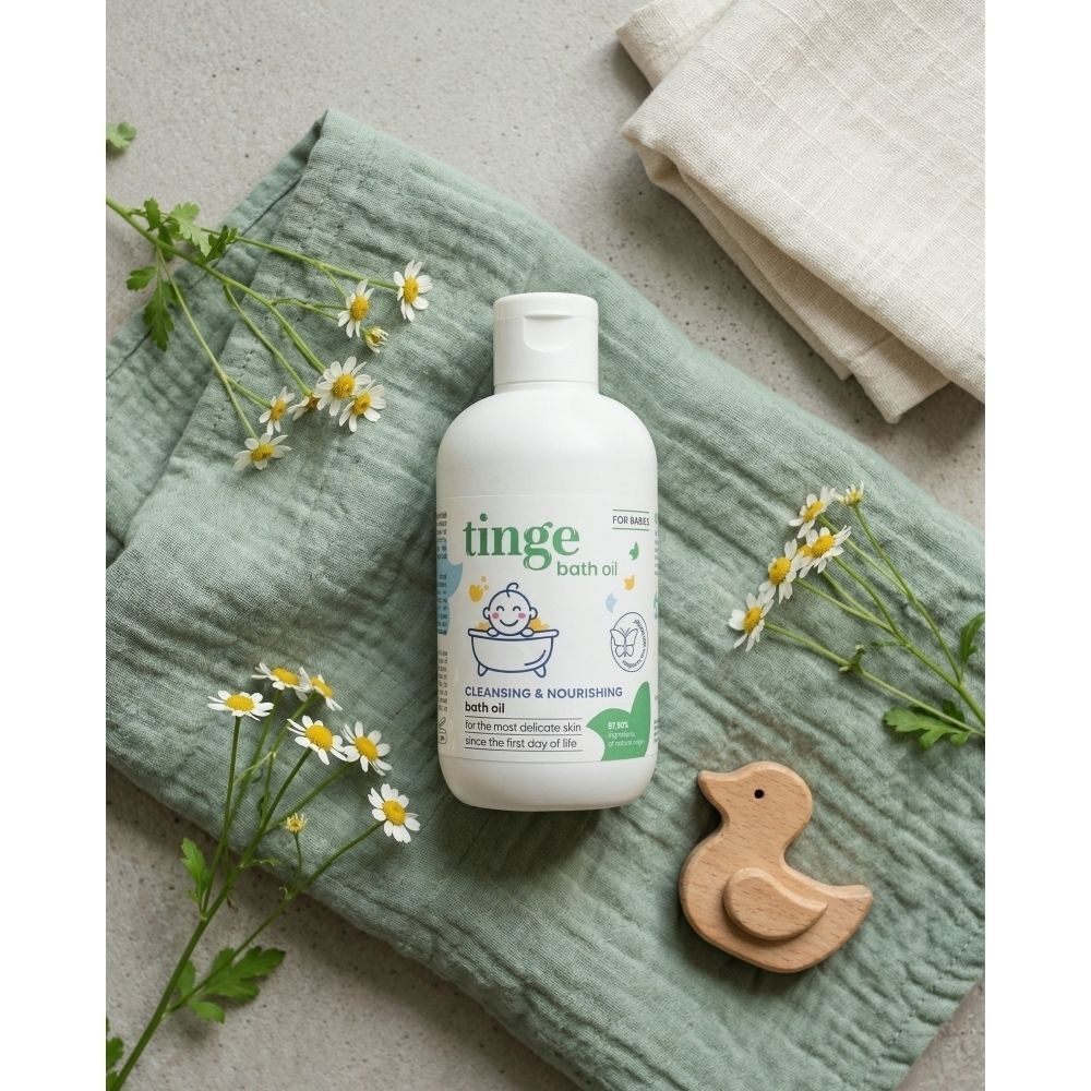 Bouteille blanche d'huile de bain Tinge, étiquette avec bébé dans une baignoire, canard en bois, fleurs de camomille.