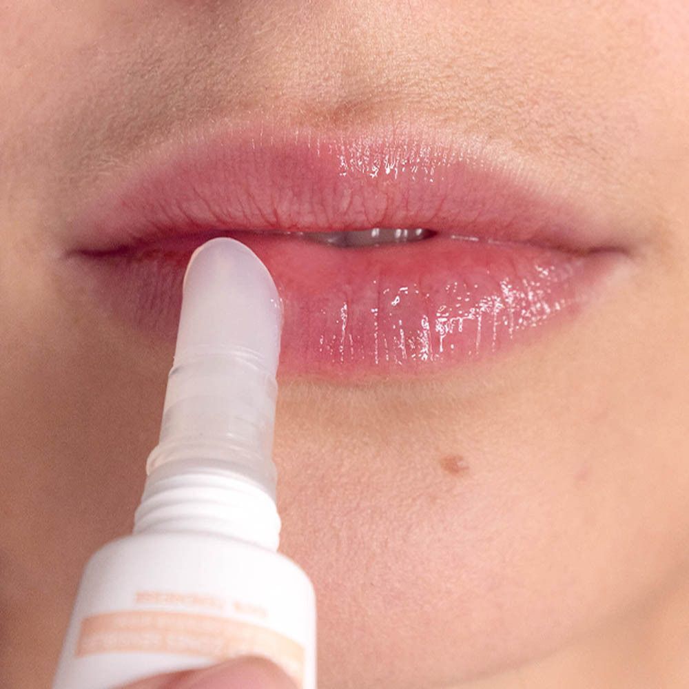 Gros plan : un applicateur dépose du baume à lèvres sur les lèvres.