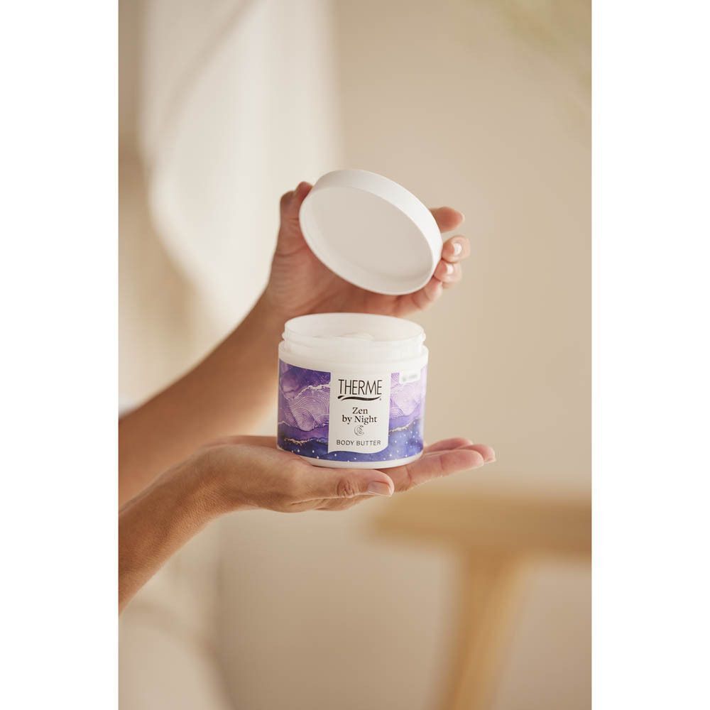 Handen die een open pot Therme Zen by Night Body Butter vasthouden.