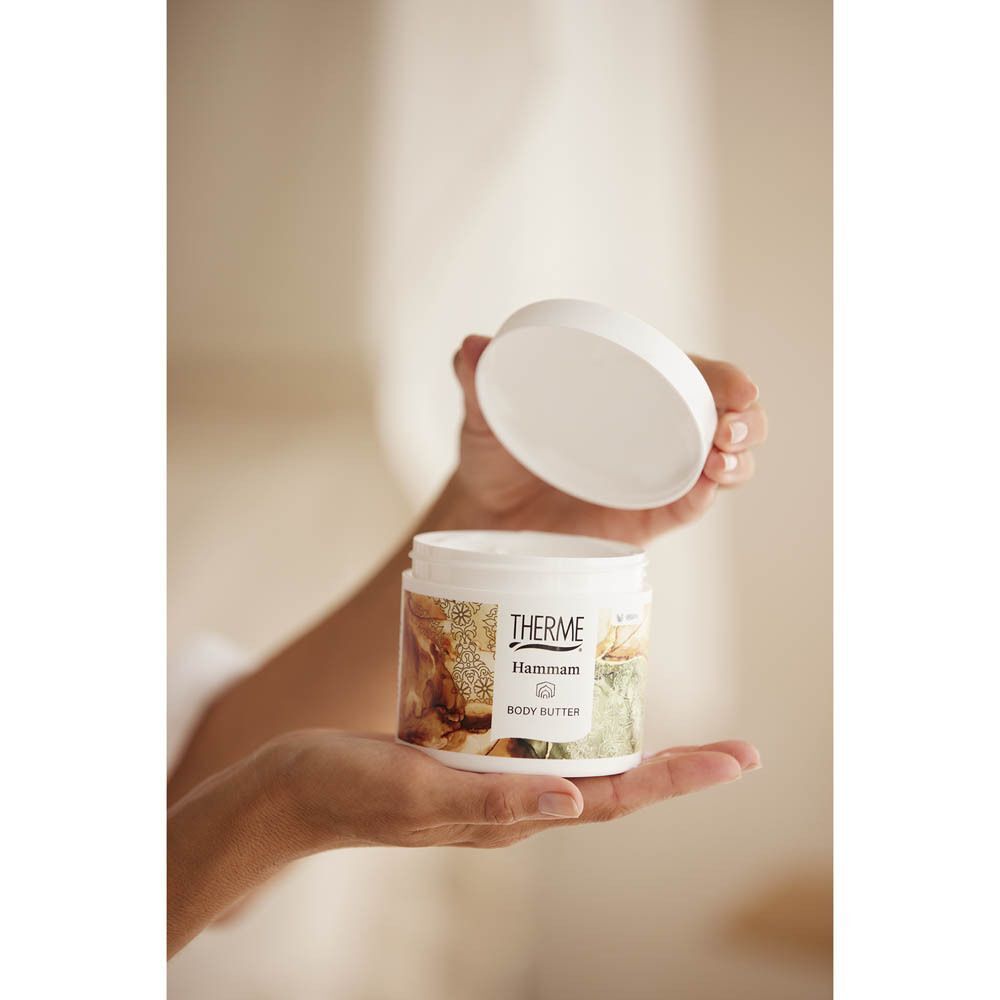 Handen openen een pot Therme Hammam Body Butter.