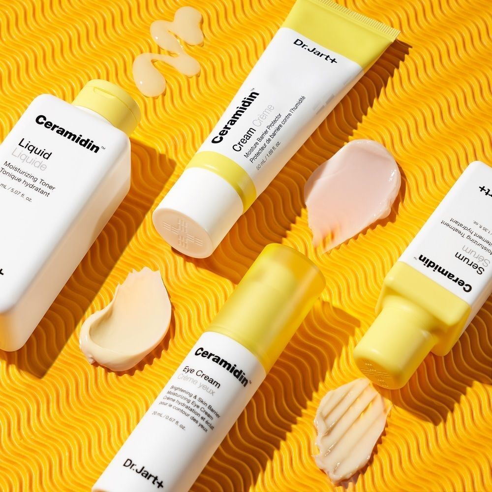 Mehrere Dr. Jart+ Ceramidinst-Produkte auf gelbem Hintergrund mit Klecksen.