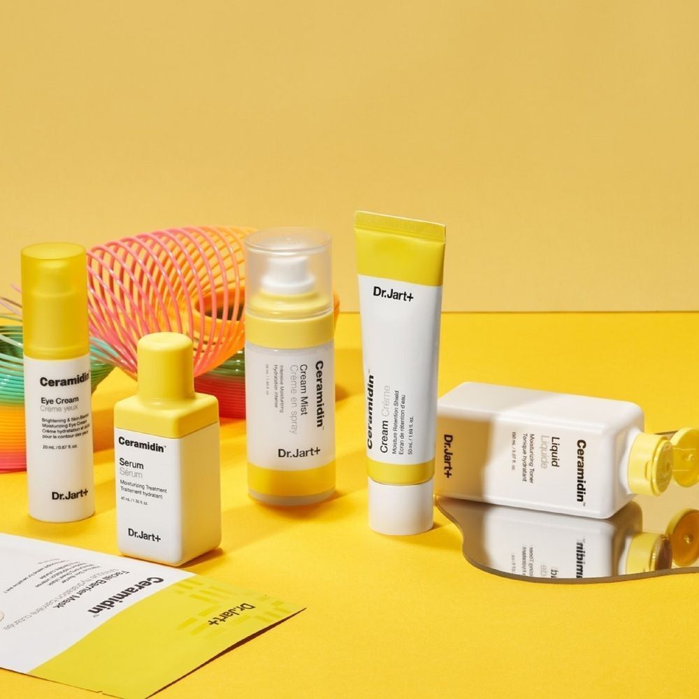 Fünf Dr. Jart+ Ceramidin Hautpflegeprodukte auf gelbem Hintergrund.