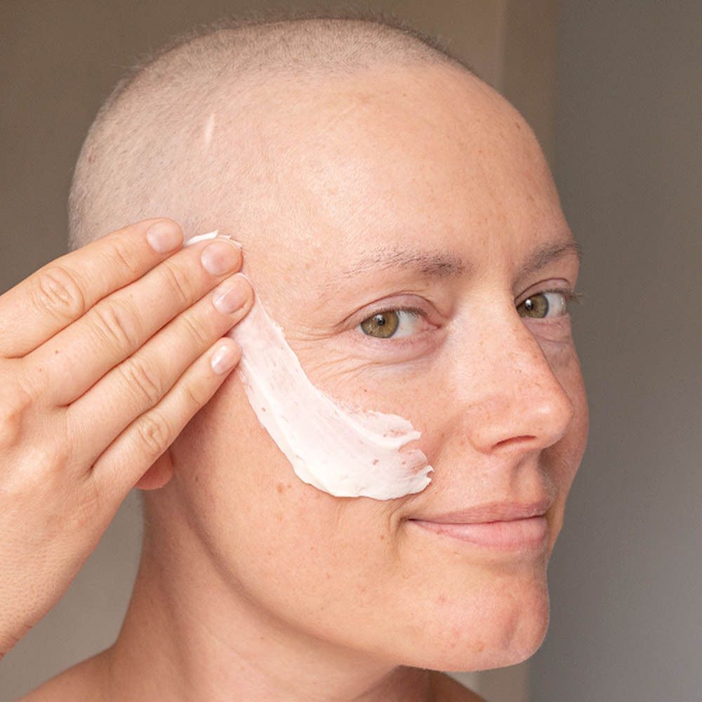 Een vrouw brengt Gezichtsmasker Ultra-Réconfortant aan op haar gezicht.