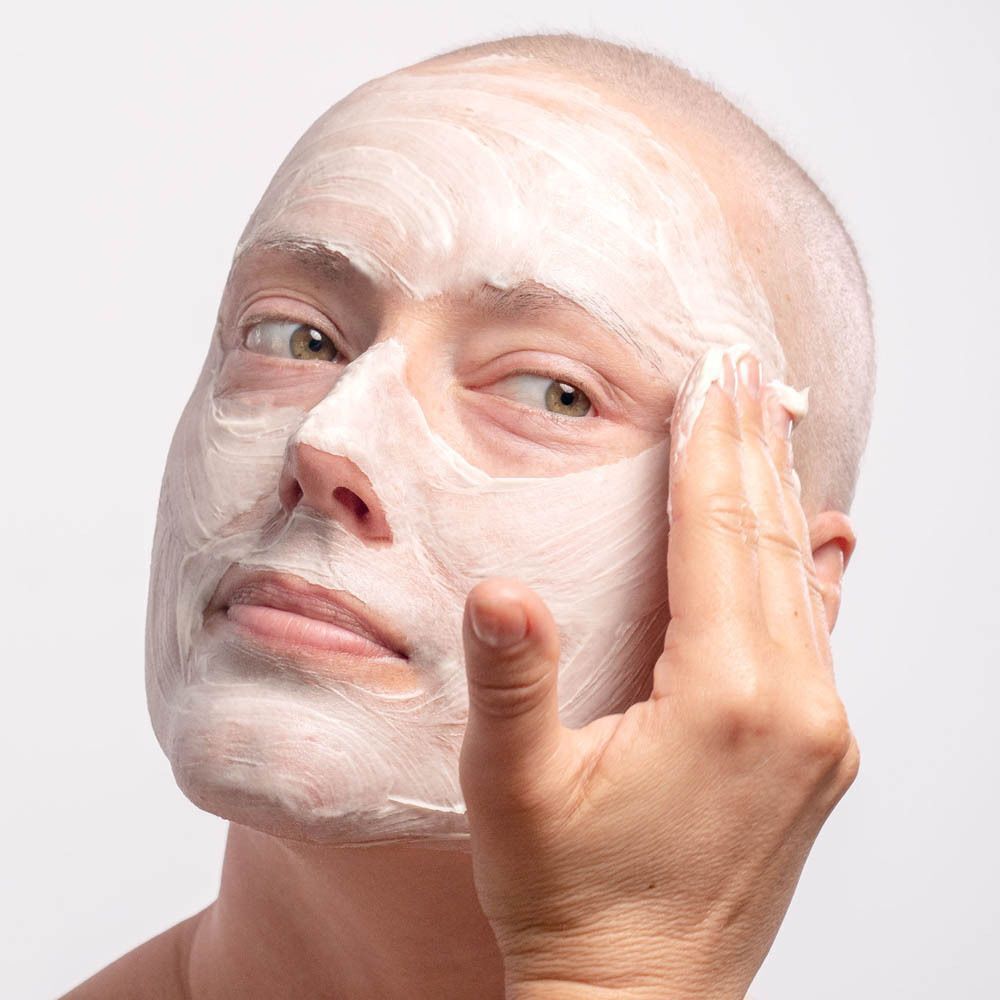 Een vrouw brengt Gezichtsmasker Ultra-Réconfortant aan op haar voorhoofd.