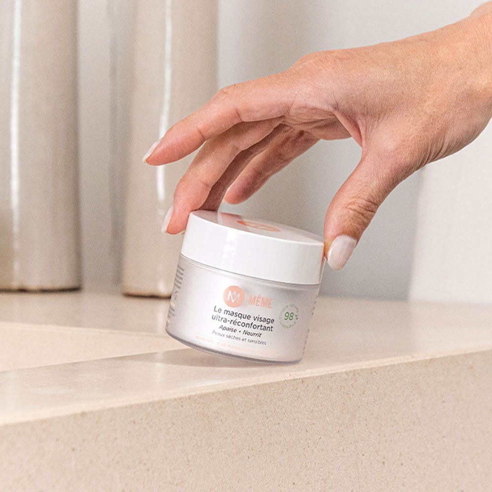 Une main tenant un pot de MÊME Le Masque Visage Ultra-Réconfortant.