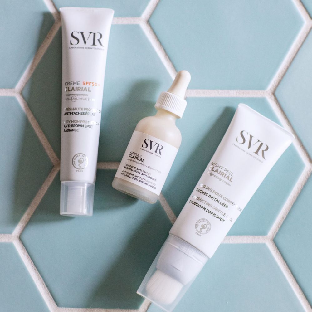 SVR Ampoule Clairial flesje en twee crèmetubes op tegelachtergrond.