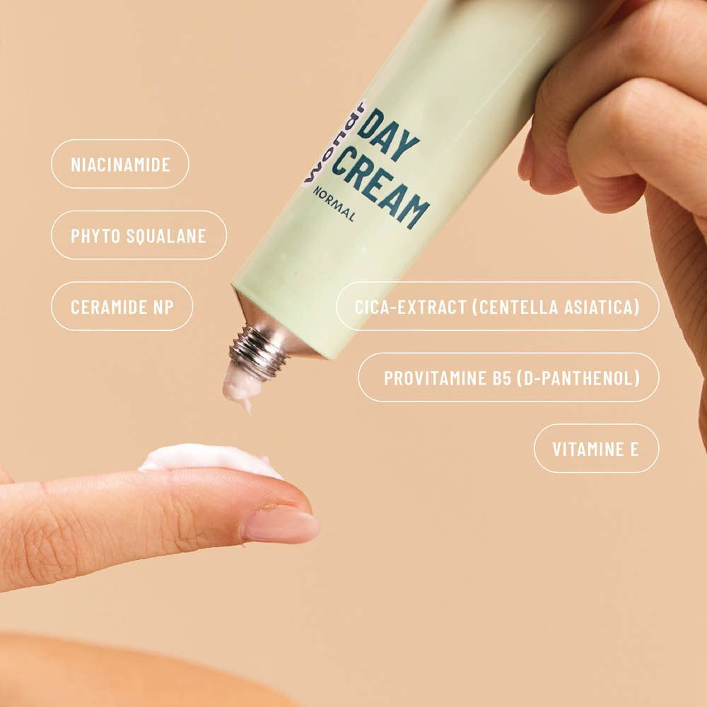 Close-up van een hand die WONDR Day Cream op een vinger doet. Ingrediënten zoals Niacinamide en Ceramide NP vermeld.