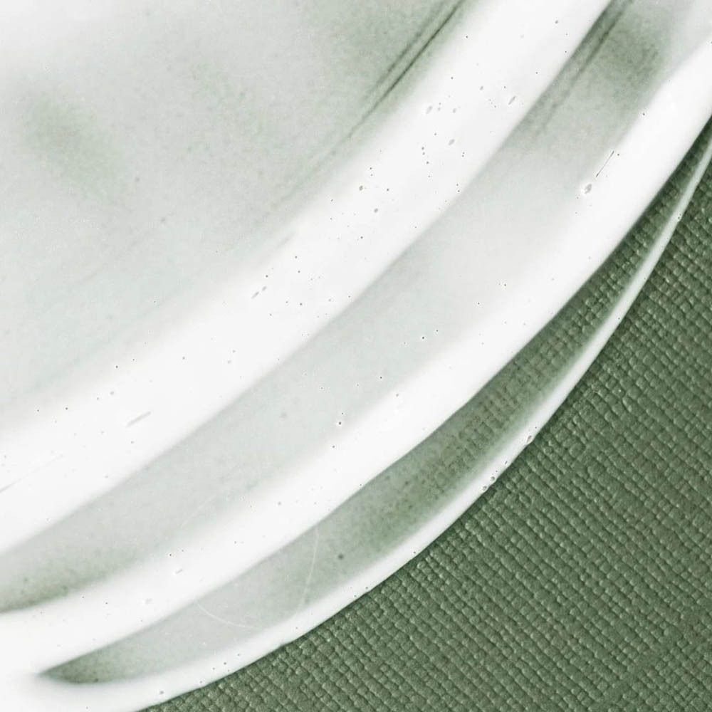 Gros plan d'une texture crème mate vert clair avec de fines bulles sur fond texturé.