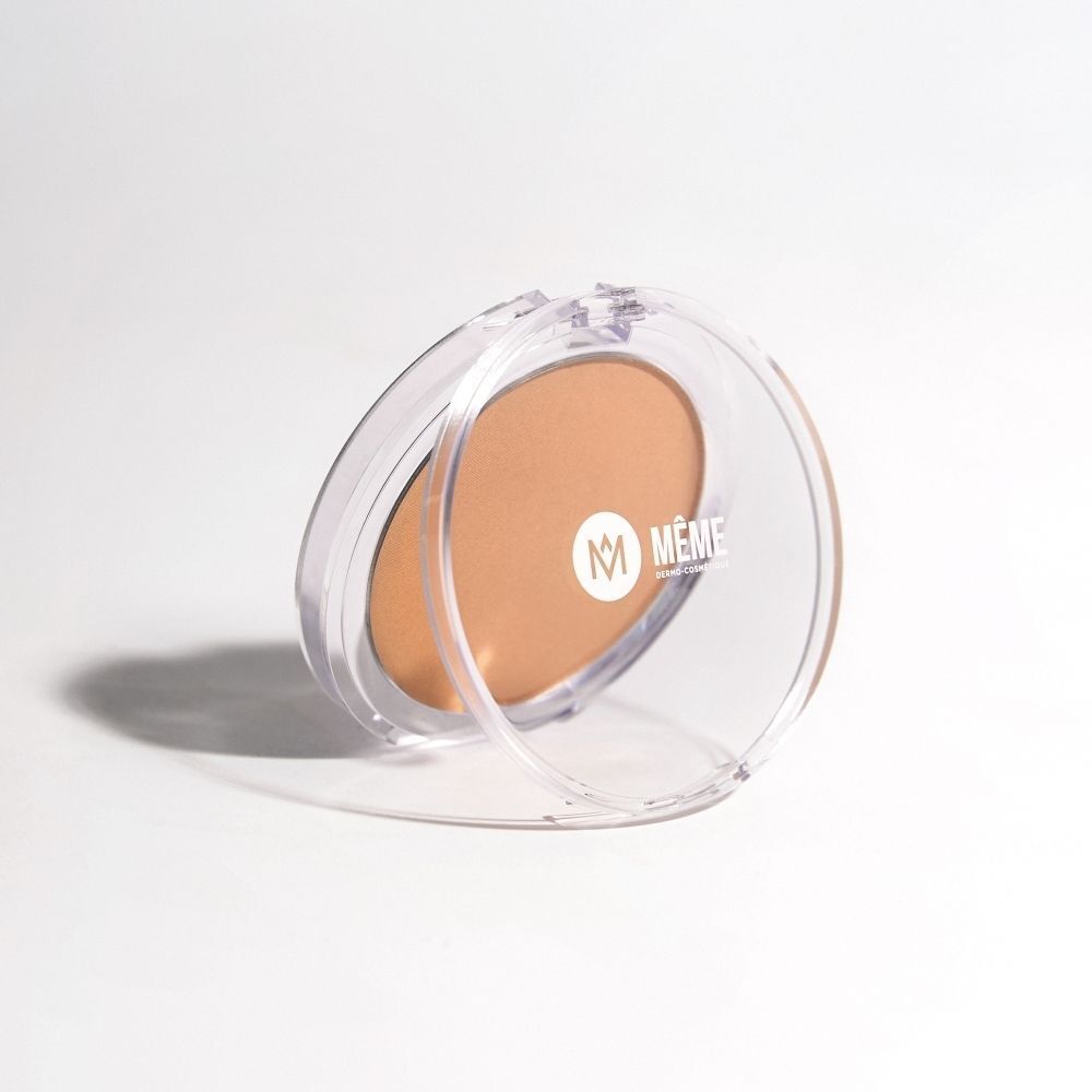 Poudre bronzante dans un boîtier transparent ouvert avec logo MÊME, posée sur le côté.