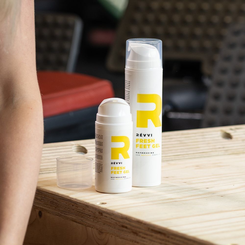 Deux flacons distributeurs blancs avec logo 'R' jaune, inscription 'RÉVVI FRESH FEET GEL', l'un ouvert.