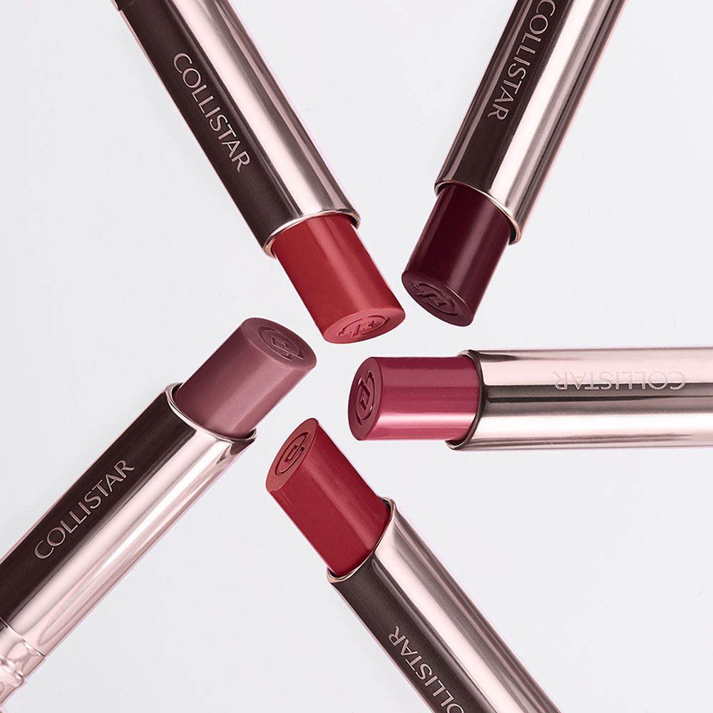 Vijf Collistar lippenstiften in diverse rode en roze tinten, met zilveren en bruine hulzen.