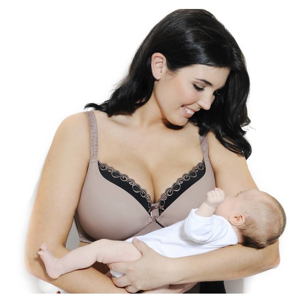 Femme tenant un bébé, portant un soutien-gorge d'allaitement beige avec de la dentelle. Regarde le bébé.