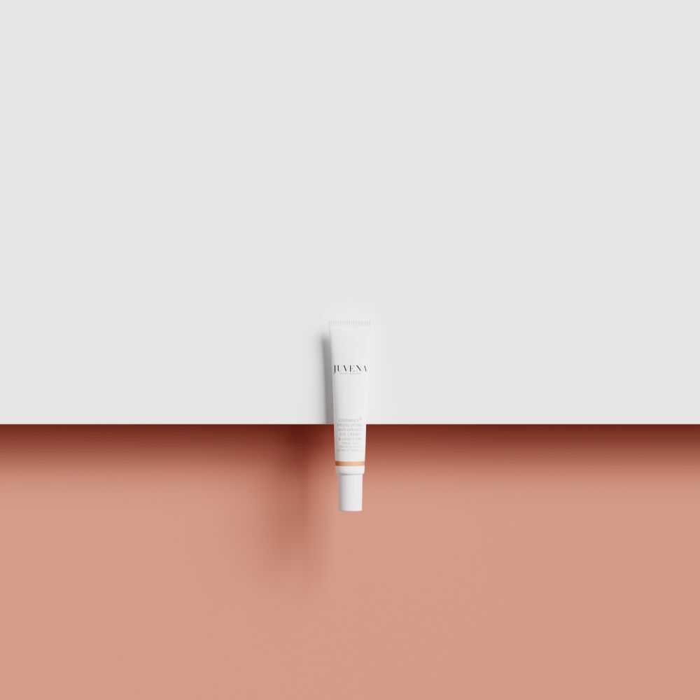 Weiße Tube auf rosa und weißem Hintergrund. Produktname und Marke nicht erkennbar.