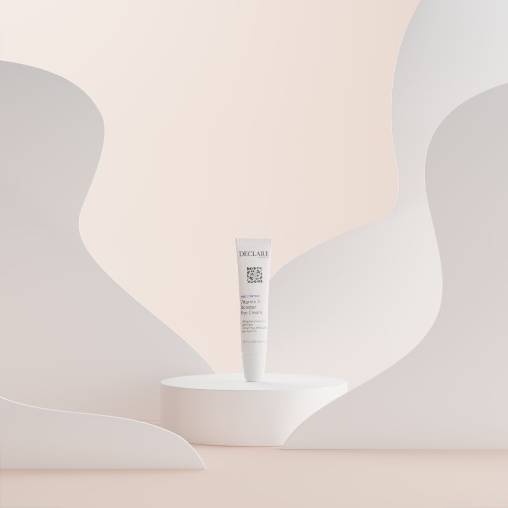Produkt auf Podest. Weiße Tube DECLARÉ Vitamin A Booster Eye Cream. Hintergrund: abstrakte Formen.