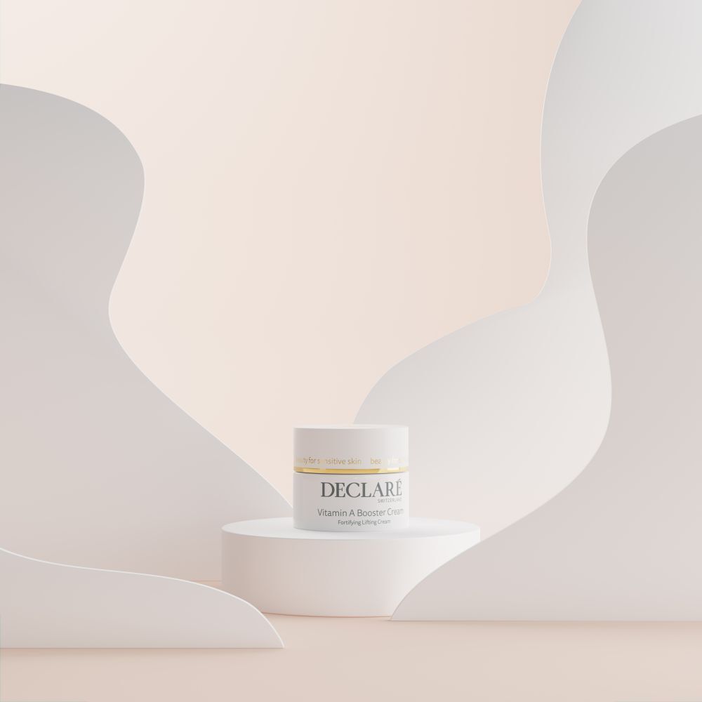 Weißes Tiegel auf Podest. Hintergrund mit weißen, geschwungenen Formen. DECLARÉ Vitamin A Booster Cream.