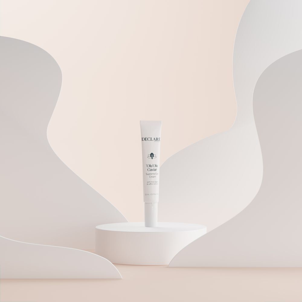 Weiße Tube 'Olu'Olu Caviar Supreme Eye Cream auf Podest. Hintergrund mit weißen Formen. DECLARÉ-Logo sichtbar.