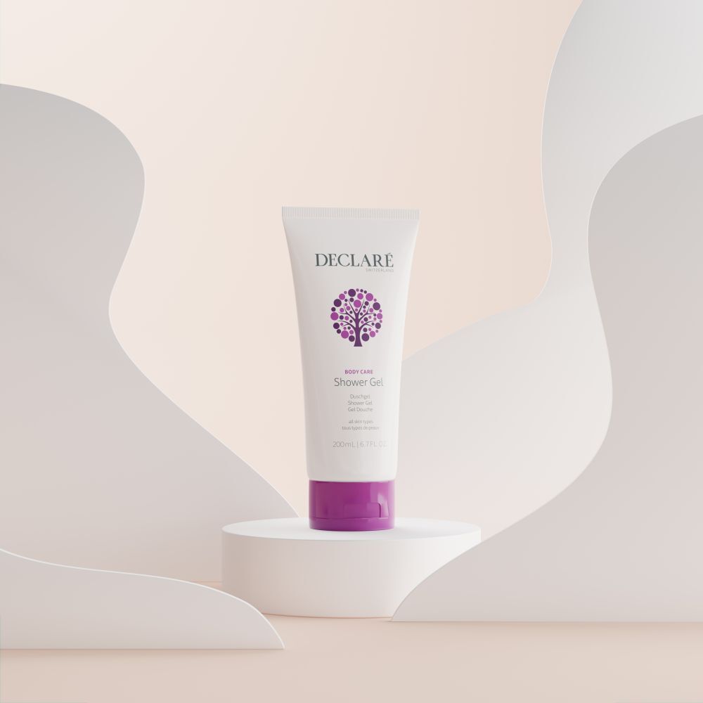Weiße Tube mit lila Verschluss auf Podest. DECLARÉ-Logo und Produktbezeichnung Shower Gel. Hintergrund mit Formen.