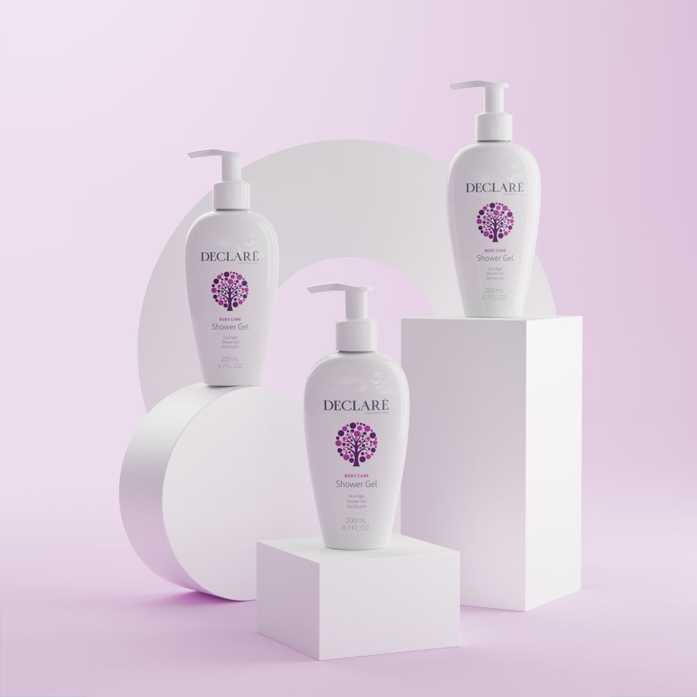 Drei weiße DECLARÉ-Flaschen mit Pumpverschluss auf Podesten. Hintergrund: weiße Formen und rosa Fläche. Produkt: Shower Gel.